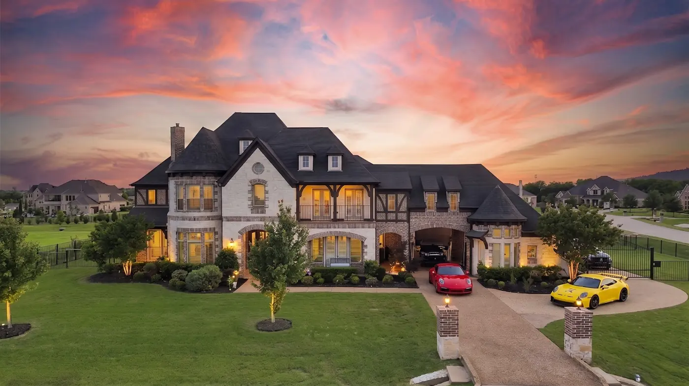 A stone and brick estate at sunset with every window lit, sold by Ann in Parker, Texas