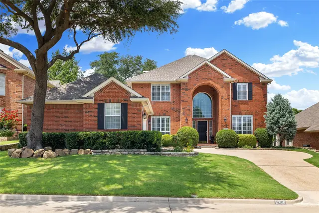 Red brick home under a large shade tree in McKinney