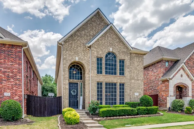 Stone two-story home with an arched window in Plano