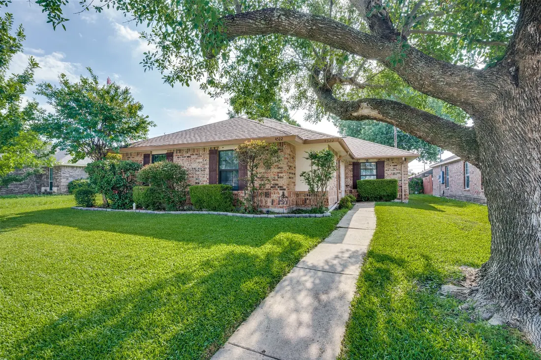 Single-story home with a mature oak in the front yard in Rowlett